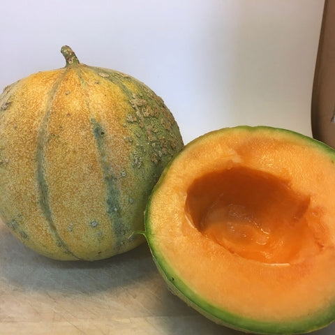 Un Melon Petit Gris de Renne est coupé en deux et posé sur une planche à découper. (Nom de marque : Tourne-Sol)