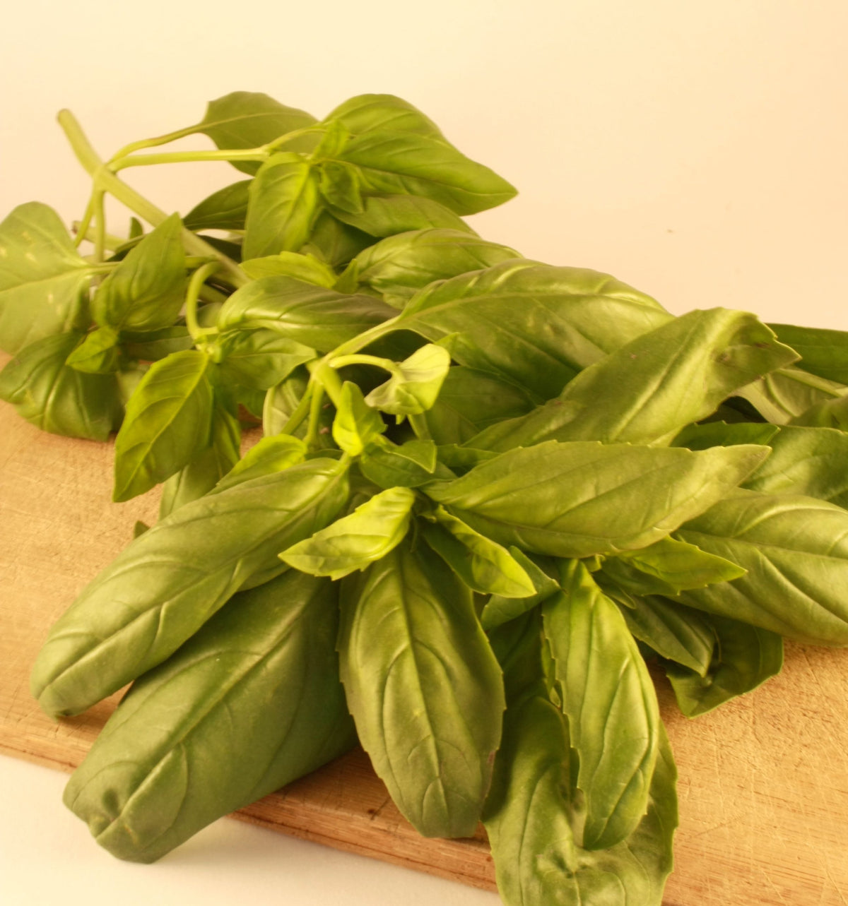 Feuilles fraîches de basilic de Gênes sur une planche à découper, parfaites pour préparer du pesto ou pour ajouter à des plats d&#39;inspiration italienne. (Tourne Sol)