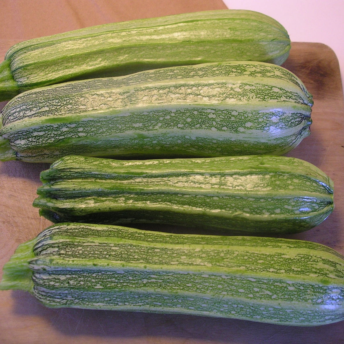 Quatre Courgettes Costata Romanesca de Tourne-Sol sur une planche à découper.